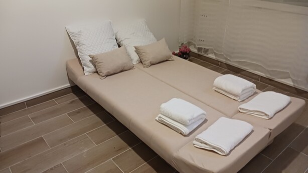 A double bed with beige bedding, two pillows, and three neatly folded white towels. - 2 rooms 37M2 4p.tout neuf.limite Paris12e.30mn DISNEY, 9mn CHAMPS ELYSEE+LOUVRE  (Vincennes)