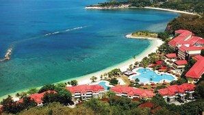 Vista aérea de un resort con varias edificaciones, una playa y una piscina.