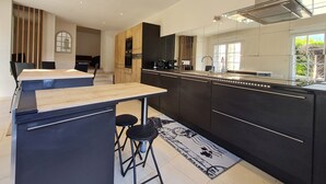 Una cocina moderna con armarios oscuros, una isla de madera y un ventanal que proporciona luz natural.