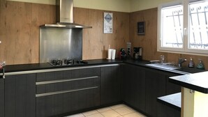 A modern kitchen with a stainless steel range hood, dark cabinetry, and a window with bars. - Villa with private pool, AC, 3 bdr, garden, parking and WIFI in Elne (Elne)