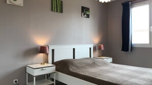 A bedroom with a bed, two bedside tables, a nightstand, a lamp, and a window with curtains. - Villa with private pool, AC, 3 bdr, garden, parking and WIFI in Elne (Elne)