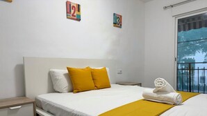 Habitación de hotel con cama, mesita de noche, ventana con vistas y una toalla sobre la cama.
