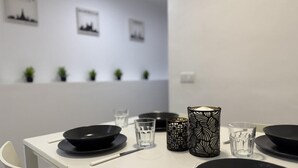 Una mesa de comedor con platos negros, vasos y un jarrón con estampado blanco y negro.