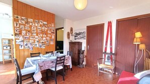 Uma área de refeições com parede de madeira decorada com fotografias, uma mesa de jantar posta com pratos e copos, e uma estátua de urso.