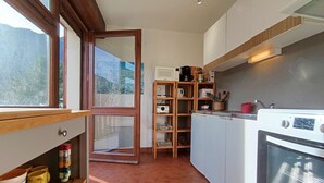 Uma cozinha compacta com forno embutido, micro-ondas e uma estante de madeira.