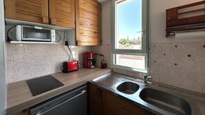 A modern kitchen with wooden cabinets, a built-in microwave, a coffee maker, and a window with a view of the city.