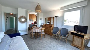 A compact living space with a dining area, a television, and a kitchenette.