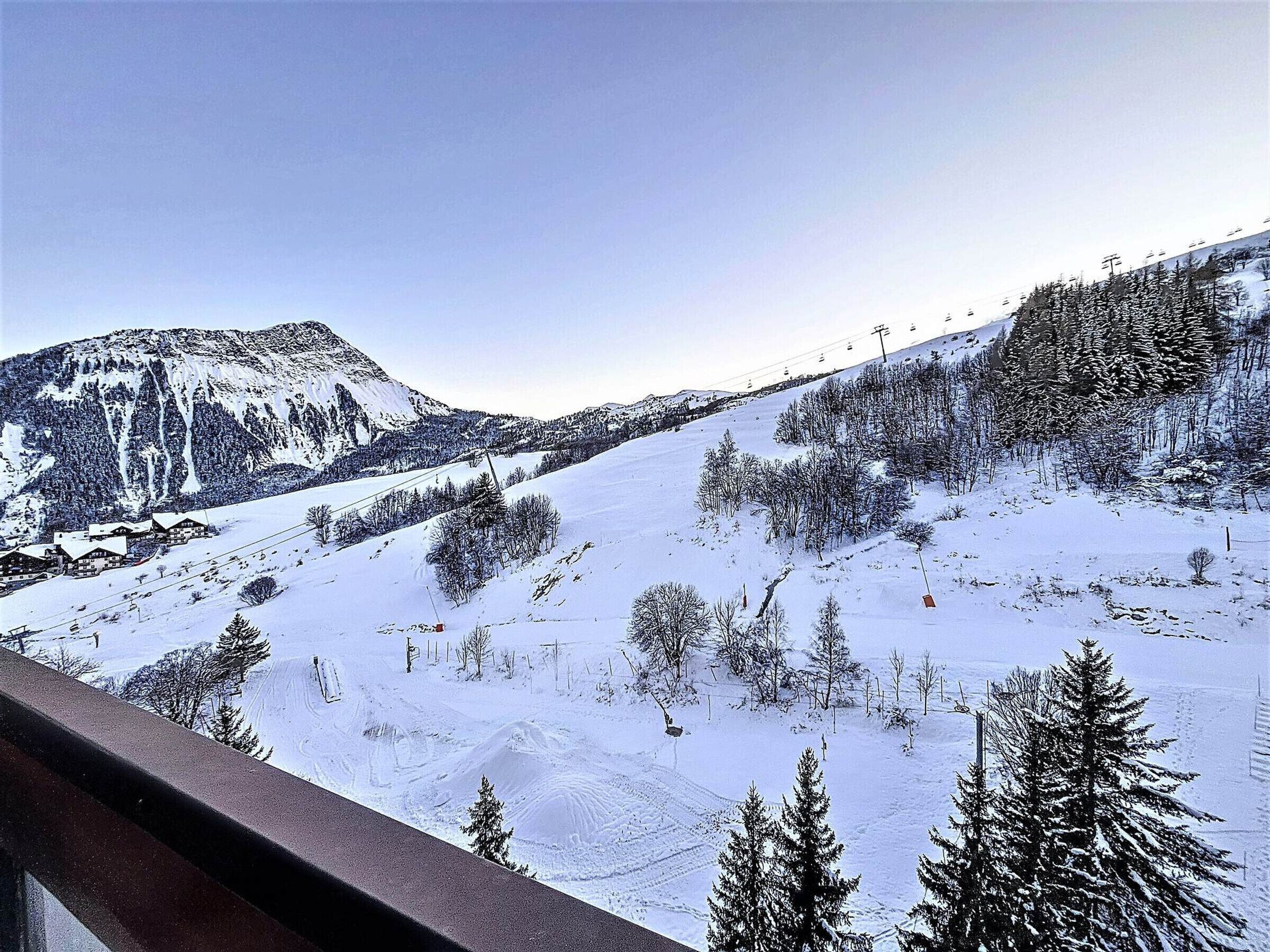 Eine verschneite Berglandschaft mit einer Seilbahn und einem Gebäude mit mehreren Dächern.