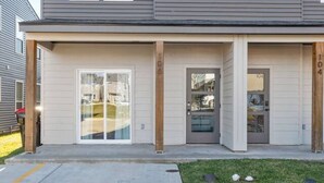 Ein zweistöckiges Mehrfamilienhaus mit Garagenzugang, einem kleinen Vorgarten und einer Betonauffahrt.