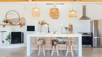 Eine moderne Küche mit Kochinsel, Pendelleuchten, integriertem Herd und einem großen Spiegel über der Insel.