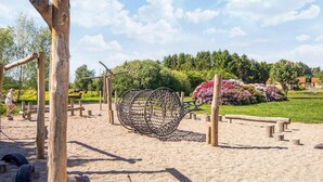 A playground with wooden structures and a large net swing.