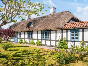 Een traditioneel vakwerkhuis met rieten dak, witte muren en blauwe raamkozijnen.