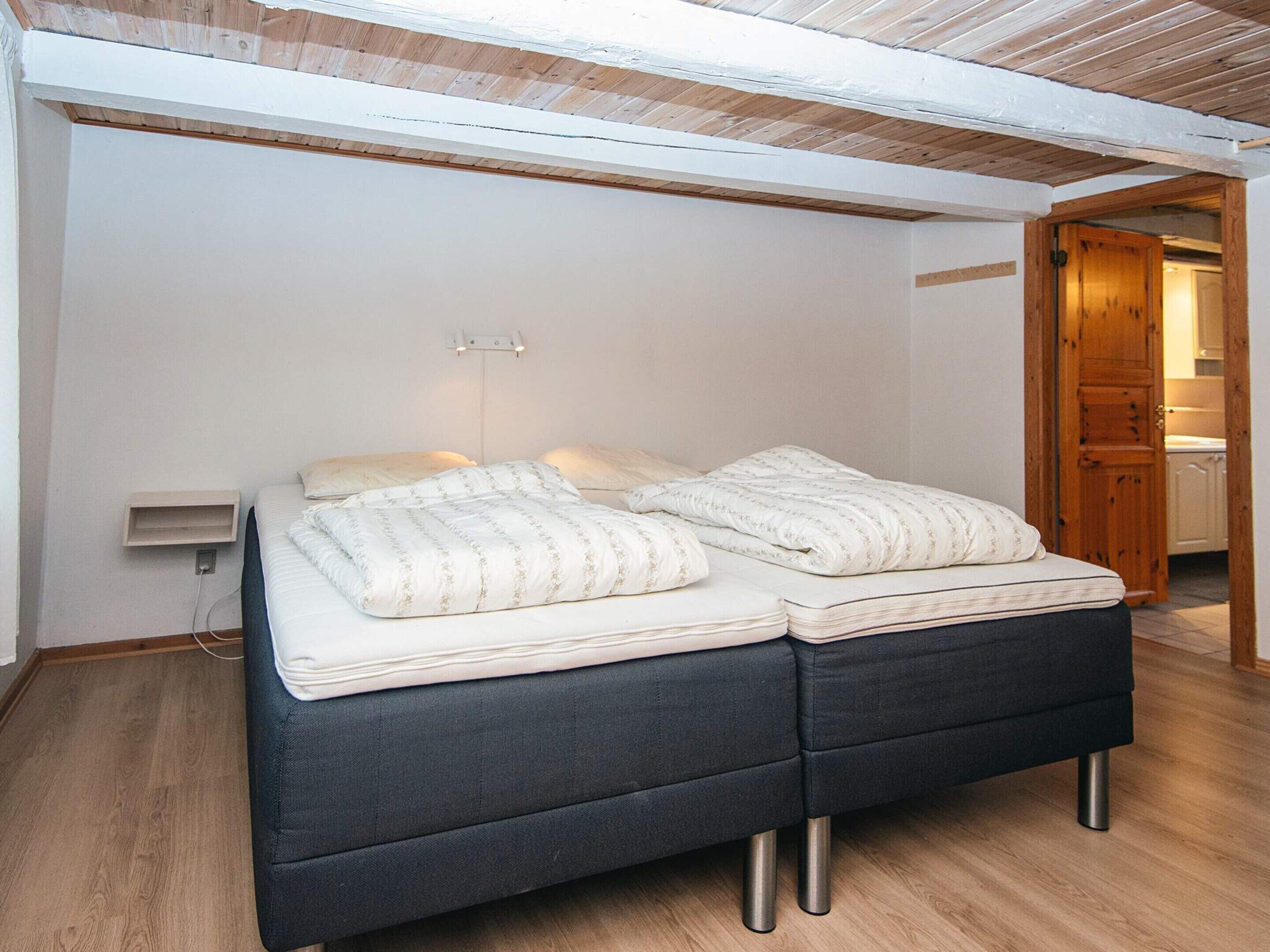 Un dormitorio con cama doble, una mesita de noche y una puerta de madera que da a un baño.