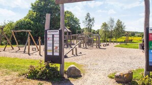 A playground with wooden structures and a signboard listing sponsors.