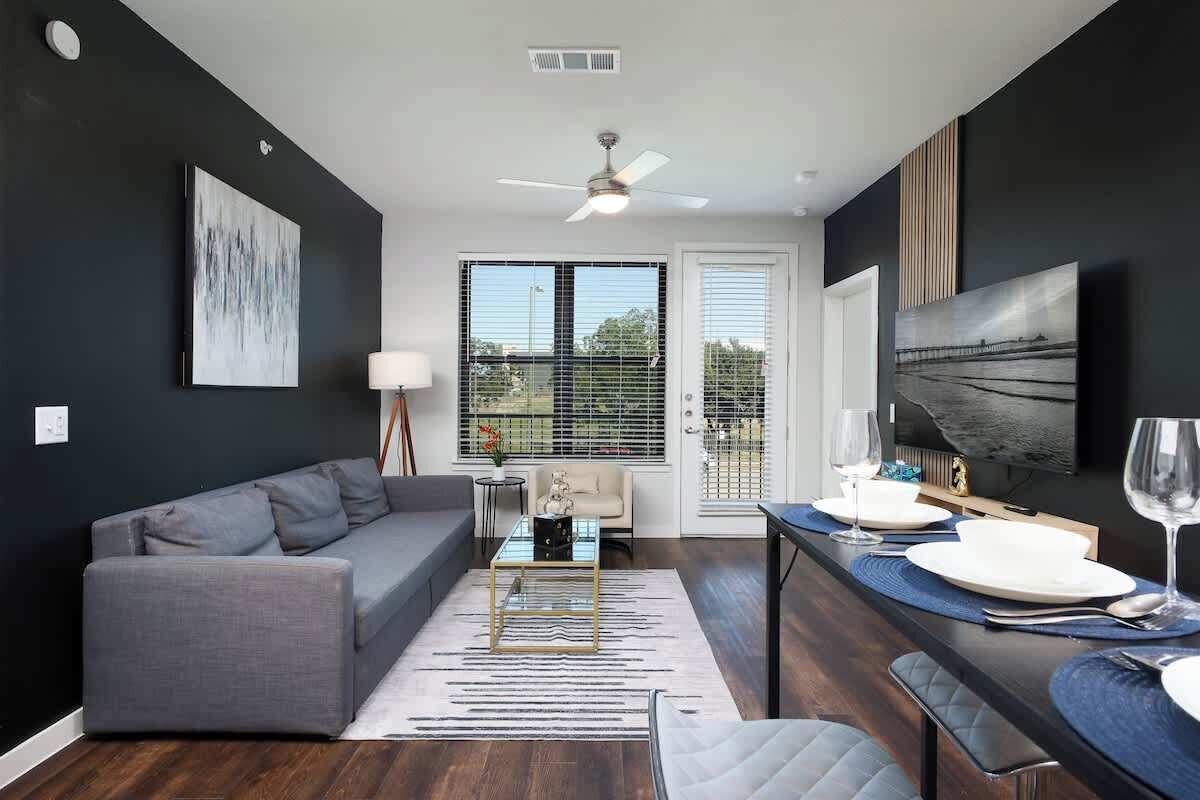 A modern living room with a gray sofa, a coffee table, and a dining area with a table set for two.