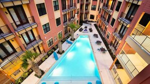 Un immeuble à plusieurs étages doté d’une piscine centrale, d’un espace extérieur aménagé et de balcons.