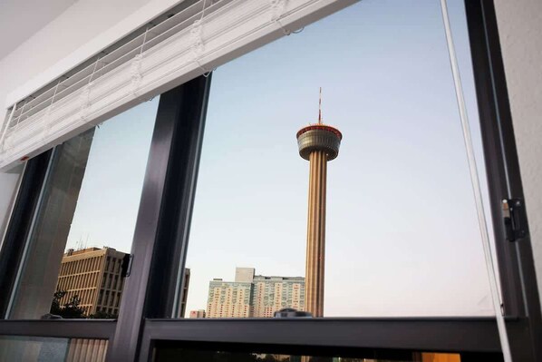 A view of a tall tower with a red top through a window with blinds.