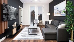 A modern living room with a grey sofa, a coffee table, and a TV mounted on the wall. - Spacious Modern 1-Bedroom, Near Riverwalk & Dome (San Antonio)