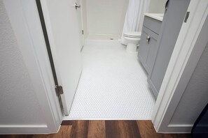 A bathroom with a white tiled floor, a toilet, and a cabinet. - Spacious Modern 1-Bedroom, Near Riverwalk & Dome (San Antonio)