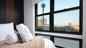 Habitación de hotel con un ventanal que ofrece vistas a una torre y al paisaje urbano.