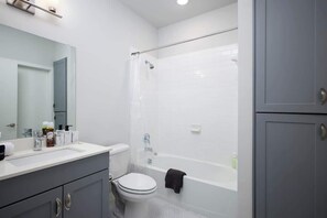 A modern bathroom with a white sink, toilet, and bathtub. - Modern 2-Bedroom Getaway Near Riverwalk & Dome (San Antonio)