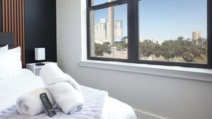 Hotelkamer met een groot bed, een raam met uitzicht op een toren en een houten paneel aan de muur.