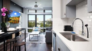 A modern kitchen with a large window, a dining area with a view, and a ceiling fan. - Downtown 1-Bedroom Stay with Gym and Free Parking (San Antonio)