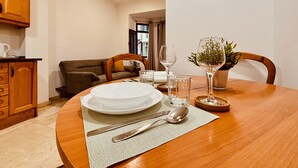 A dining area with a wooden table set for two, a sofa, and a kitchen area with wooden cabinets. - Click&Guest - 1Naval Nautical Ap. in Gran Canaria (Las Palmas de Gran Canaria)