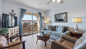 Una sala de estar con televisor, sofá y un balcón con vistas.