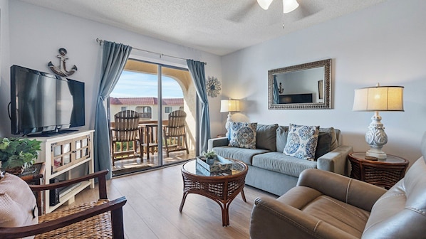 A living room with a TV, sofa, and a balcony with a view.