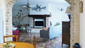 A dining area with a stone archway, a fireplace, and a cozy seating arrangement.