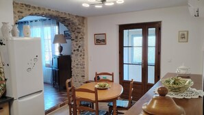 A kitchen with a dining table, chairs, a refrigerator, and a stone wall.