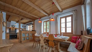 A rustic wooden interior with a dining area, wooden chairs, a bench, and a kitchen with wooden cabinets and a stove. - Chalet Baker Vacation Home (Pettneu am Arlberg)