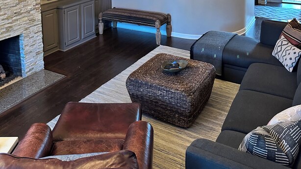Amplia sala de estar con un sofá grande, chimenea, televisor y una escalera que lleva a un nivel superior.