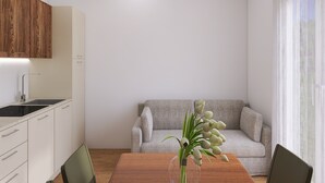 A modern kitchen with white cabinets and a wooden countertop, a dining table with chairs, and a grey sofa with a vase of flowers. - Apartment Villa in Limone Sul Garda (Limone sul Garda)