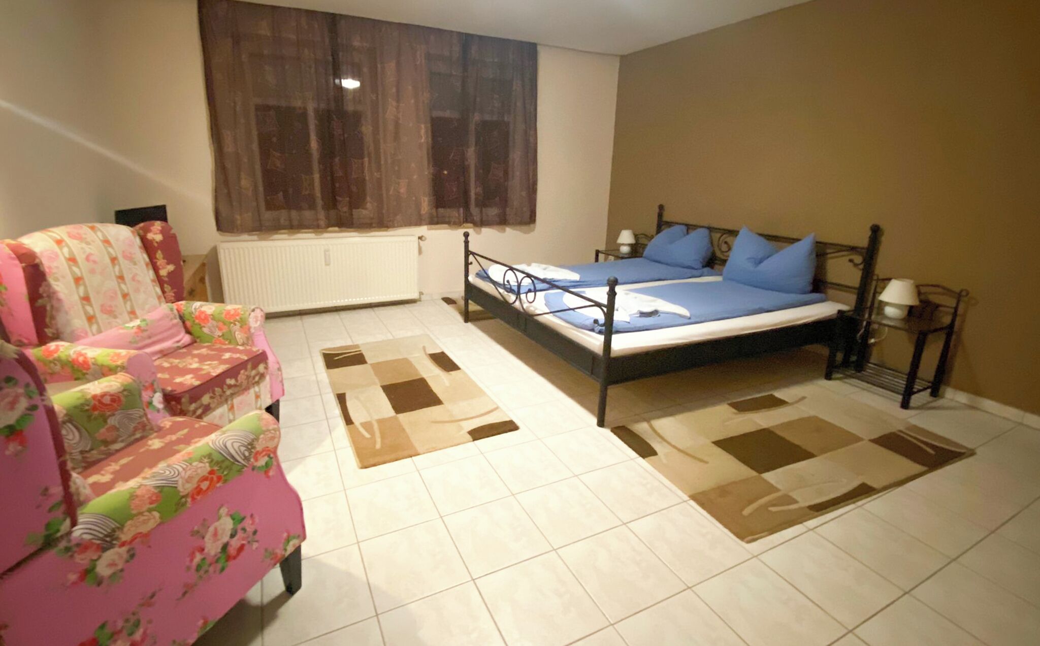 Une chambre à coucher avec un lit, un canapé, une fenêtre et un radiateur.