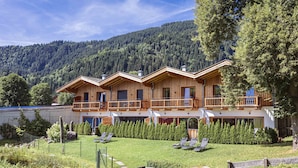 A wooden chalet with a balcony, surrounded by a well-maintained garden and a forested mountain backdrop. - Penthouse mit 2 Schlafzimmern (Reith bei Kitzbuehel)