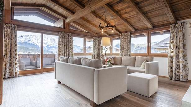 A cozy living room with a wooden ceiling, large windows with curtains, and a sofa set. - Penthouse mit 2 Schlafzimmern (Reith bei Kitzbuehel)