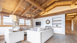 A modern living room with a wooden ceiling, white sofas, a flat-screen TV, and a fireplace. - Penthouse mit 2 Schlafzimmern (Reith bei Kitzbuehel)