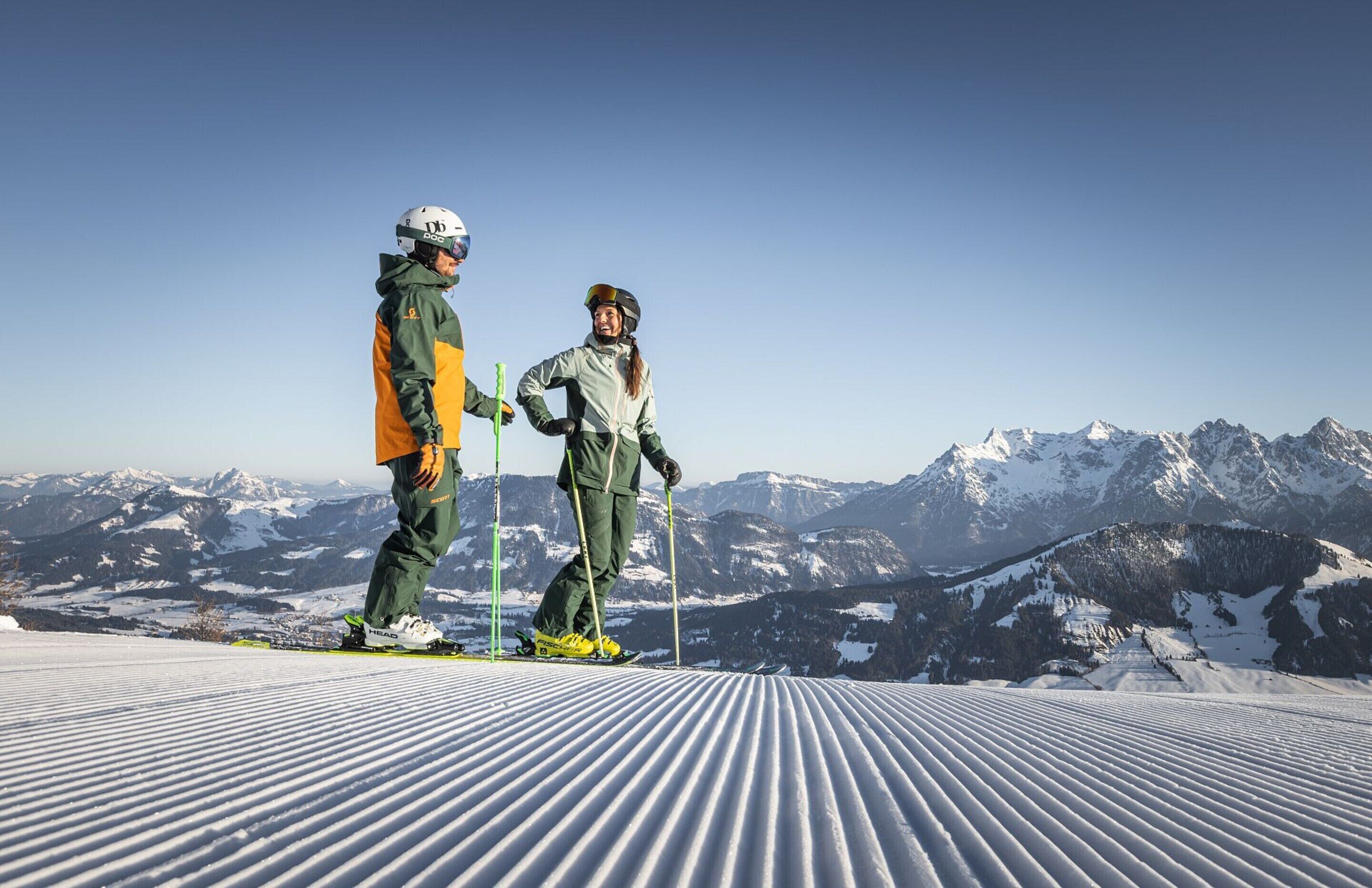 Two skiers on a snowy slope with a mountain backdrop.
