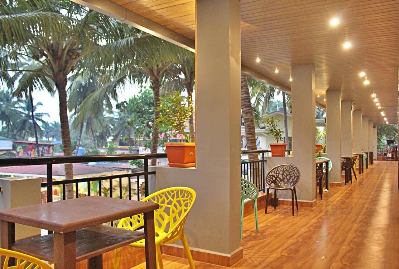 An indoor area with wooden flooring, chairs, and tables arranged along a corridor with a railing.