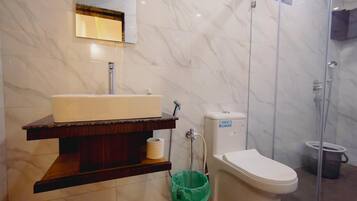 A bathroom with a marble wall, a sink, a toilet, and a shower enclosure.