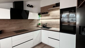 A modern kitchen with white cabinetry, a wooden countertop, and built-in appliances including a stove and oven. - Premium Apartment Seaview (Porec)