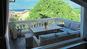 A balcony with a wicker sofa, a small table, and potted plants. - Premium Apartment Seaview (Porec)