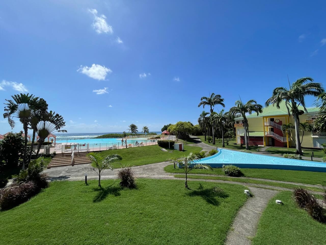 Un resort con piscina, palmeras y vista al océano.