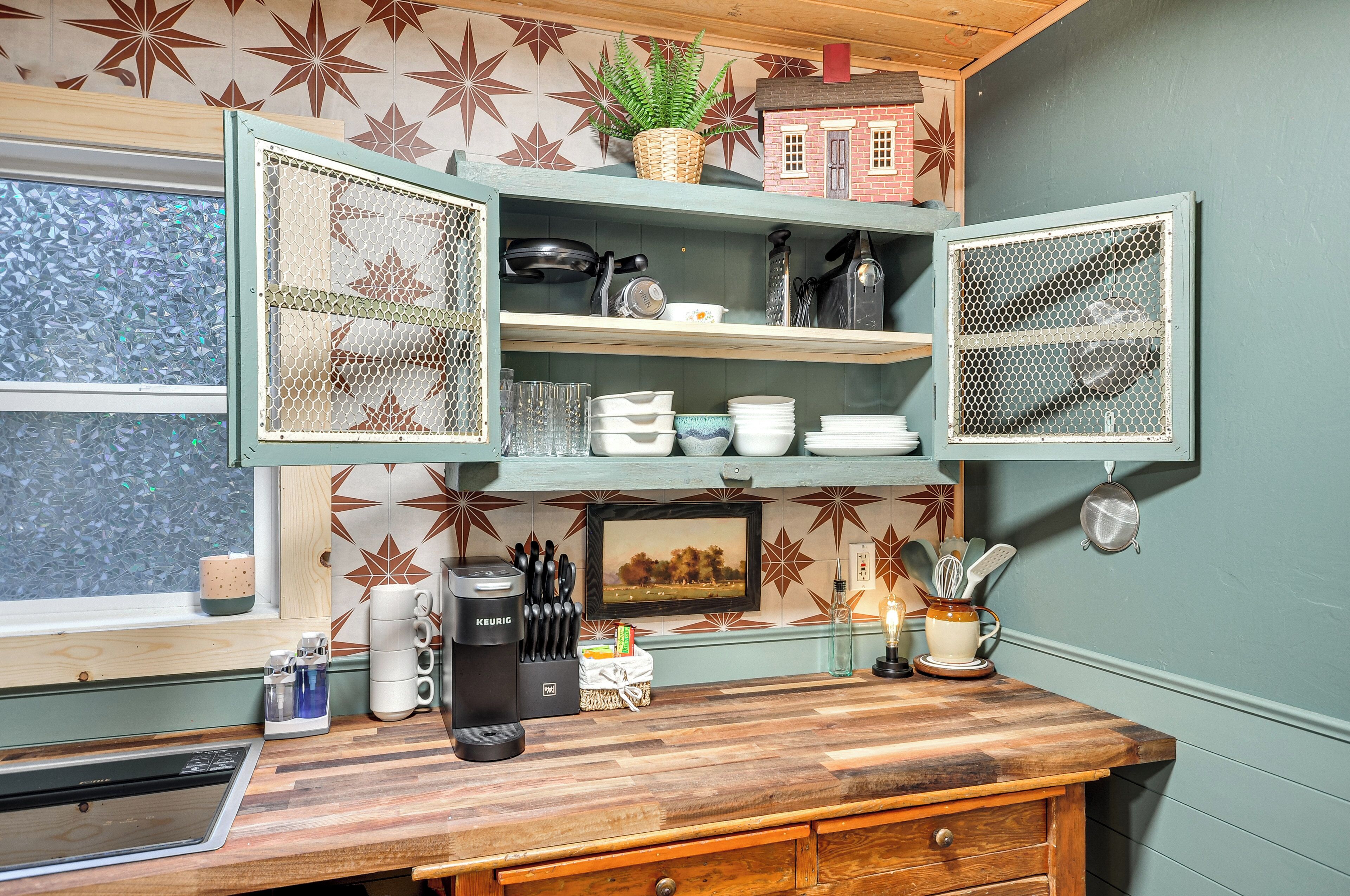 A kitchen with open shelves, a coffee maker, and a window with a view.