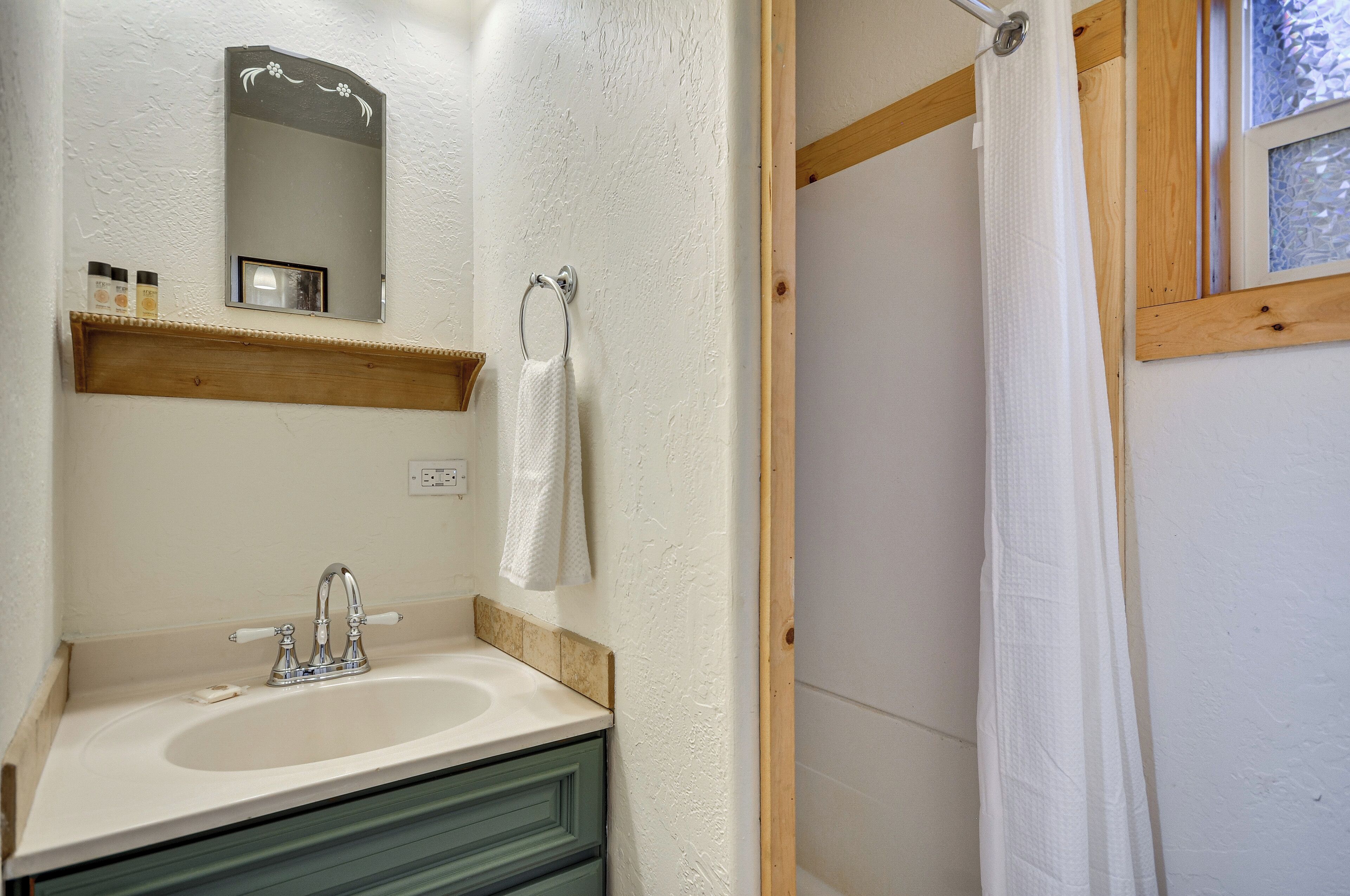 A bathroom with a sink, mirror, towel rack, and a shower curtain.