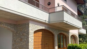 Un bâtiment à deux étages, doté d’une façade en pierre, de portes en bois et d’un balcon avec des rampes en métal.