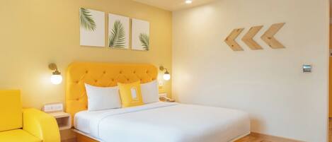 Una habitación de hotel con una cama y un sillón amarillos, además de una mesita.