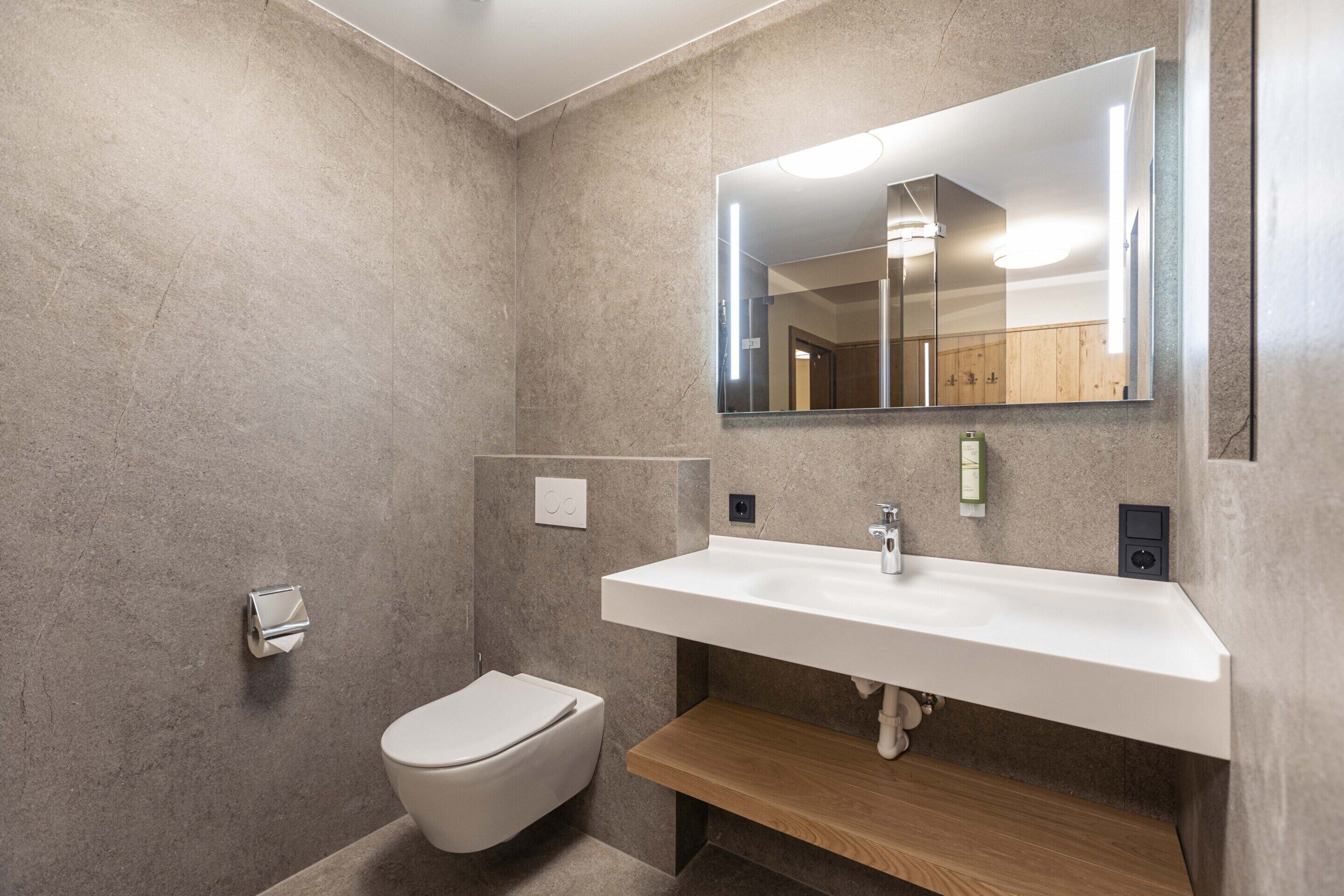 Une salle de bain moderne avec un lavabo blanc, un miroir et des toilettes.